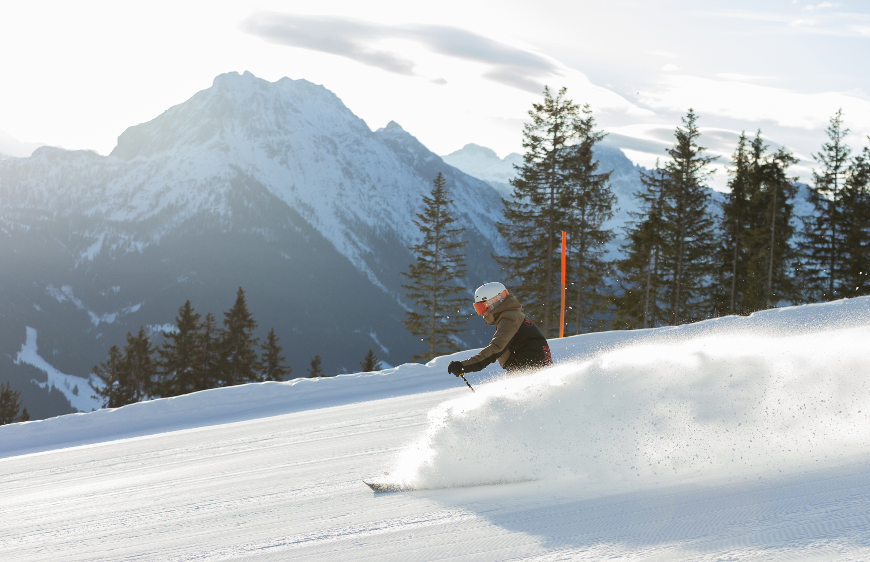 Skifahrer auf einer schneebedeckten Piste in den Alpen bei Sonnenschein